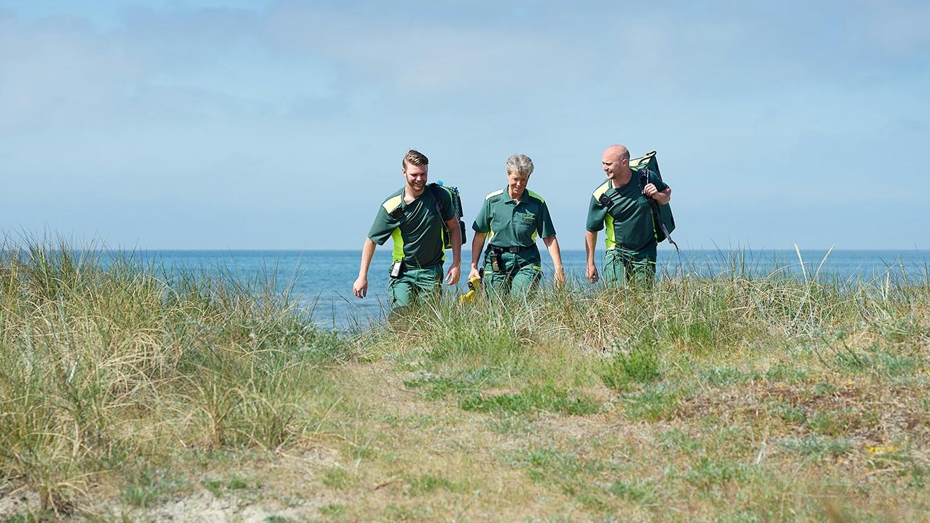 EMS professionals in green workwear by the sea