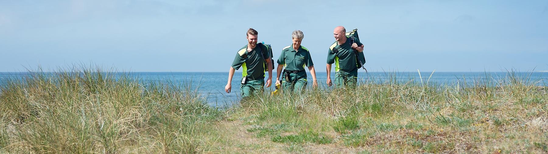 EMS professionals in green workwear by the sea